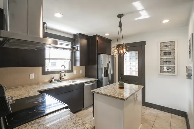a kitchen with stainless steel appliances granite countertop a sink a stove and a refrigerator