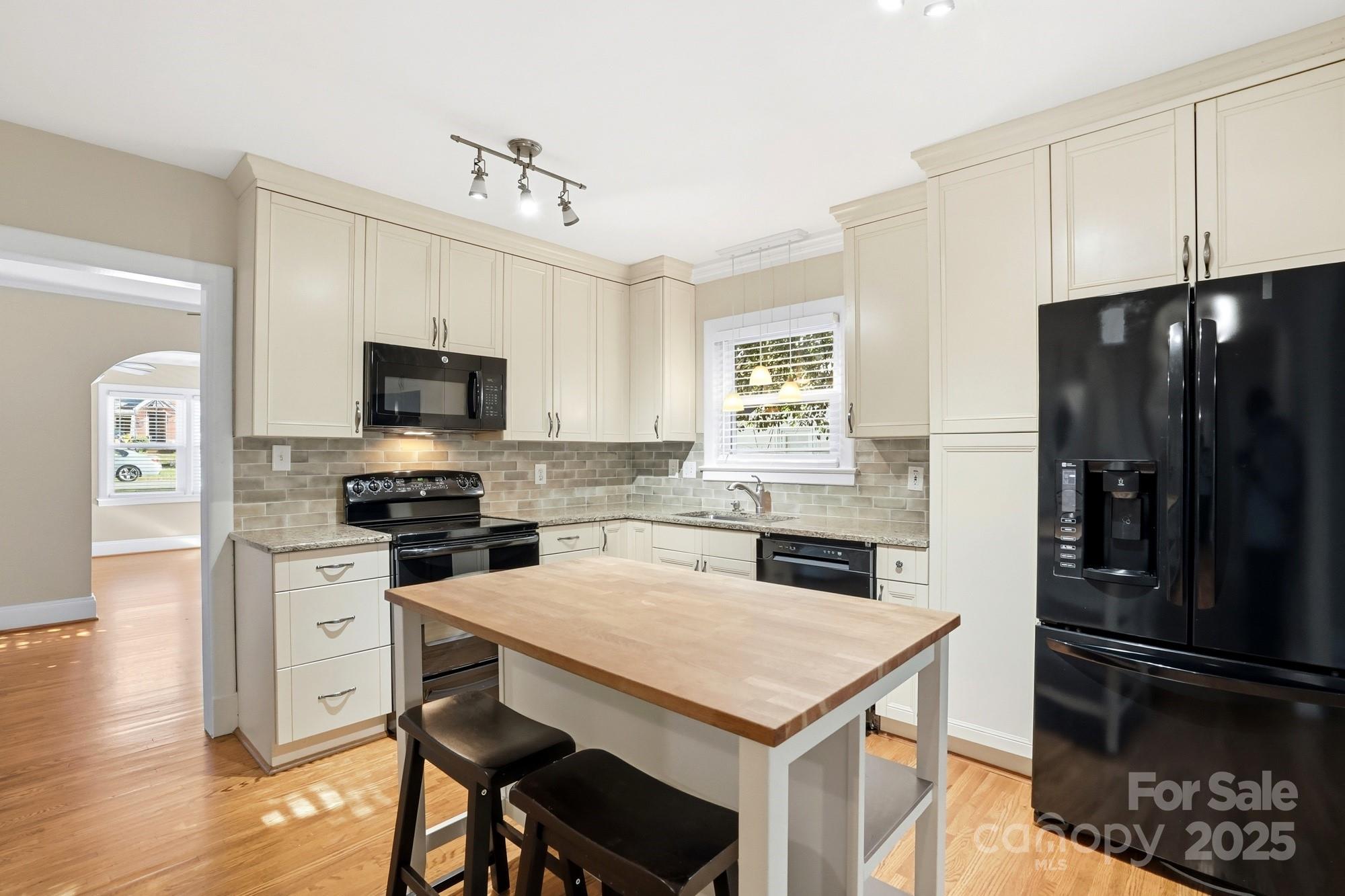 3108 Westmoreland Avenue Charlotte, NC 28205 - Photo 6 of 27 a kitchen with a refrigerator a stove a microwave and island with wooden floor