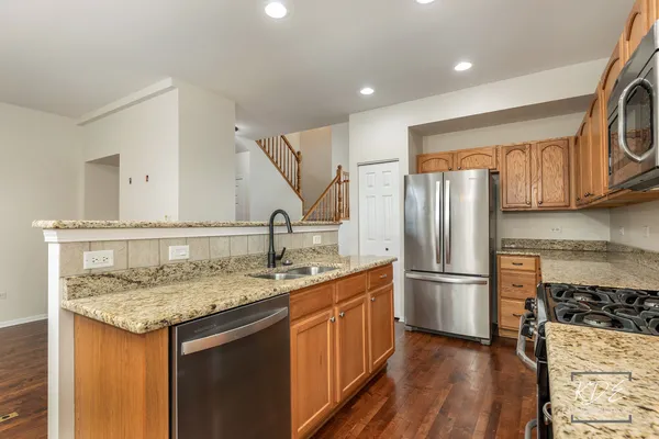 a kitchen with sink a refrigerator and wooden cabinets