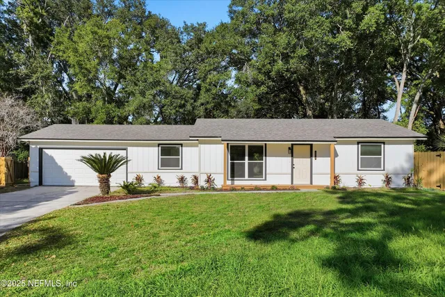 a front view of a house with a garden and trees