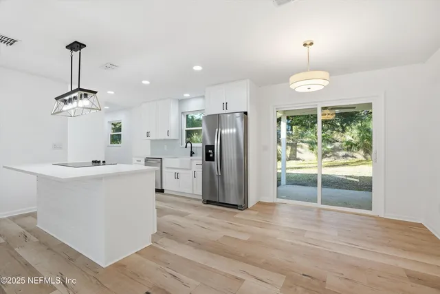a kitchen with kitchen island white cabinets stainless steel appliances and chandelier