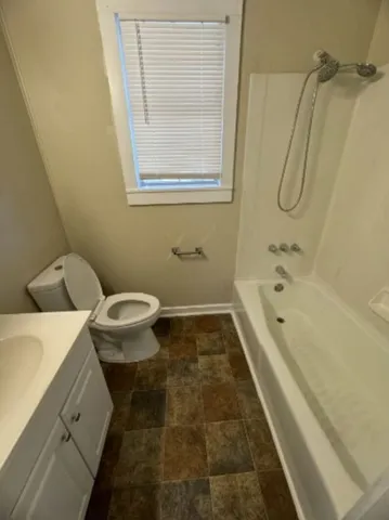 a bathroom with a granite countertop sink a toilet and shower