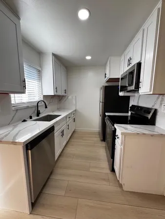 a kitchen with kitchen island granite countertop a sink and a stove top oven
