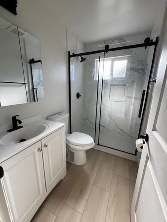 a bathroom with a granite countertop sink toilet and shower