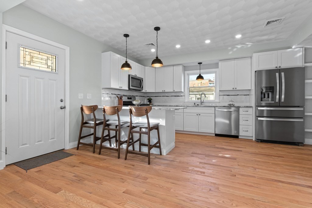 57 Buffum Street, Unit 1 Salem, MA 01970 - Photo 5 of 31 a kitchen with stainless steel appliances granite countertop a sink a stove a refrigerator and island with wooden floor