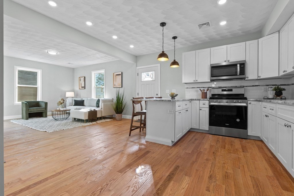 57 Buffum Street, Unit 1 Salem, MA 01970 - Photo 8 of 31 a kitchen with stainless steel appliances granite countertop a stove top oven a sink dishwasher and a refrigerator with wooden floor