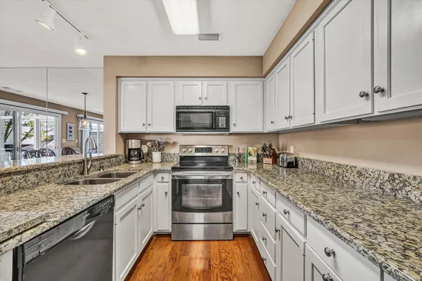 a kitchen with granite countertop a sink stainless steel appliances and cabinets