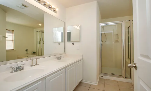 a bathroom with a double vanity sink mirror and shower