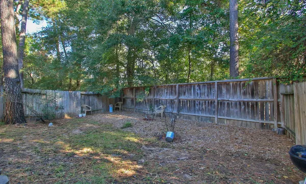 a view of a backyard with a trees and wooden fence