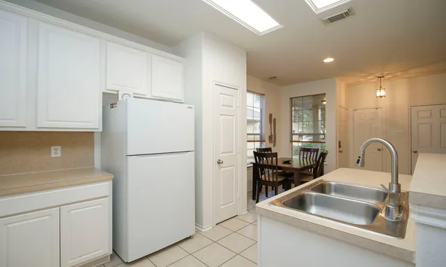 a kitchen with a refrigerator sink and white cabinets