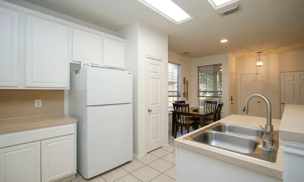 a kitchen with a refrigerator sink and white cabinets