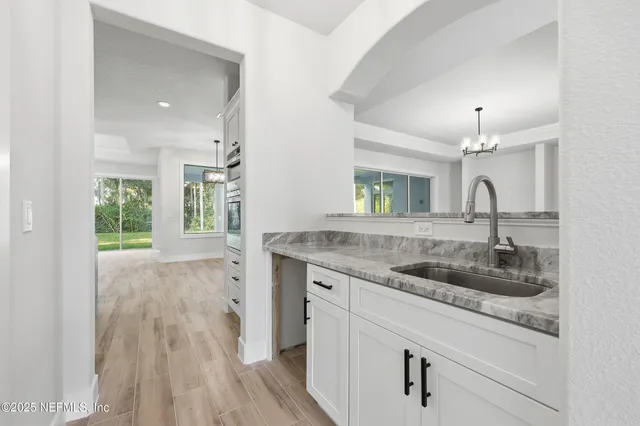 an empty room with wooden floor chandelier fan and windows