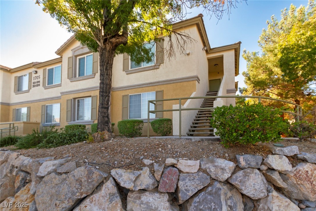 Rear view of house with stairs and stucco siding