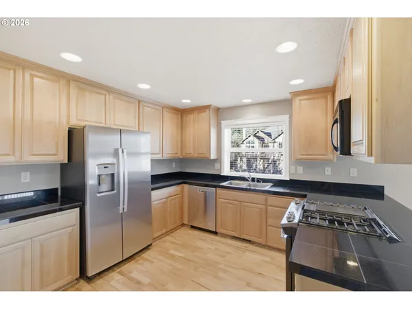 a kitchen with stainless steel appliances granite countertop a stove a sink and a refrigerator