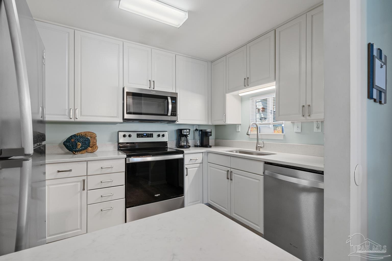 16470 Perdido Key Drive, Unit A 24 Perdido Key, FL 32507 - Photo 12 of 60 a kitchen with white cabinets and stainless steel appliances