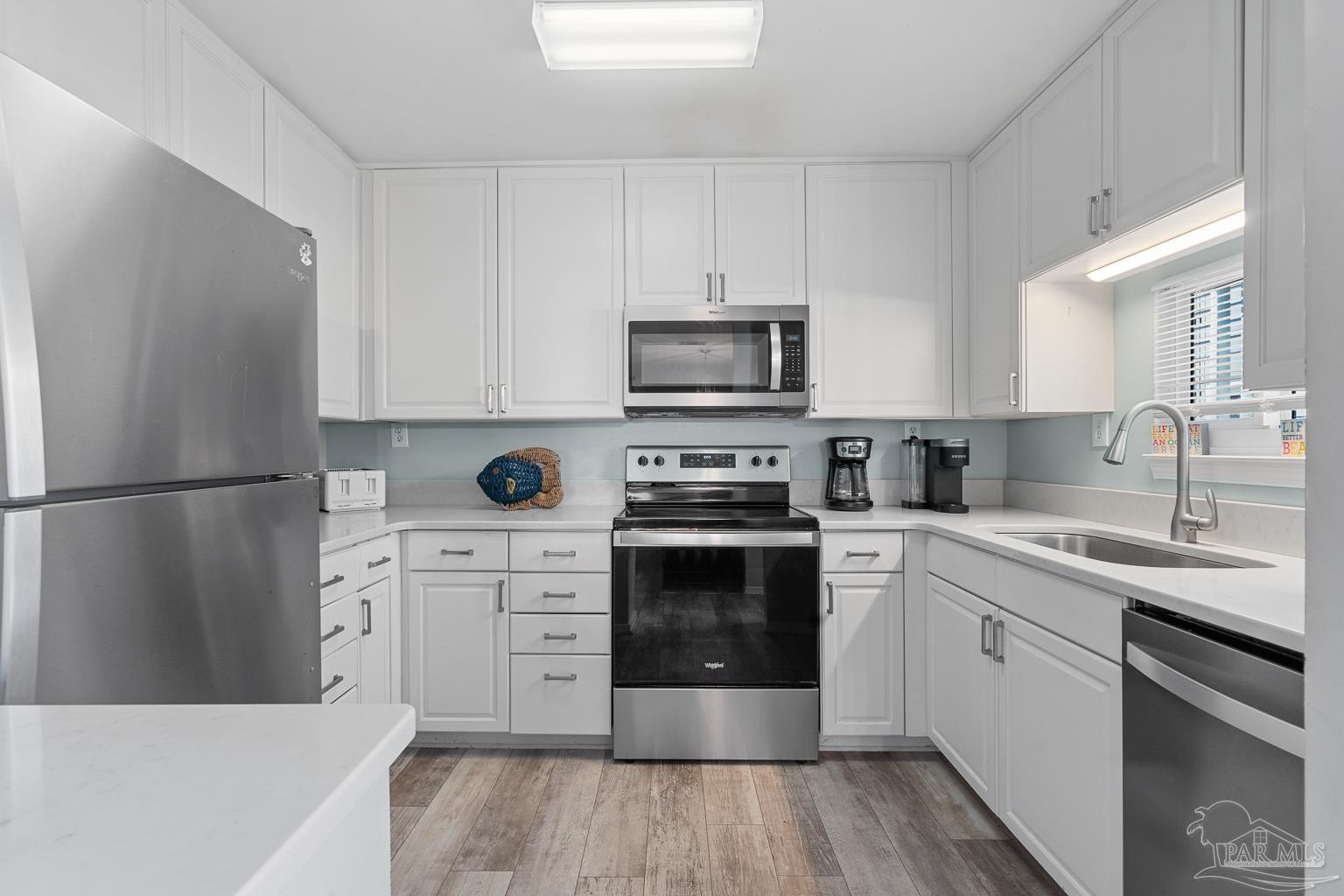 16470 Perdido Key Drive, Unit A 24 Perdido Key, FL 32507 - Photo 13 of 60 a kitchen with cabinets stainless steel appliances a sink and wooden floor