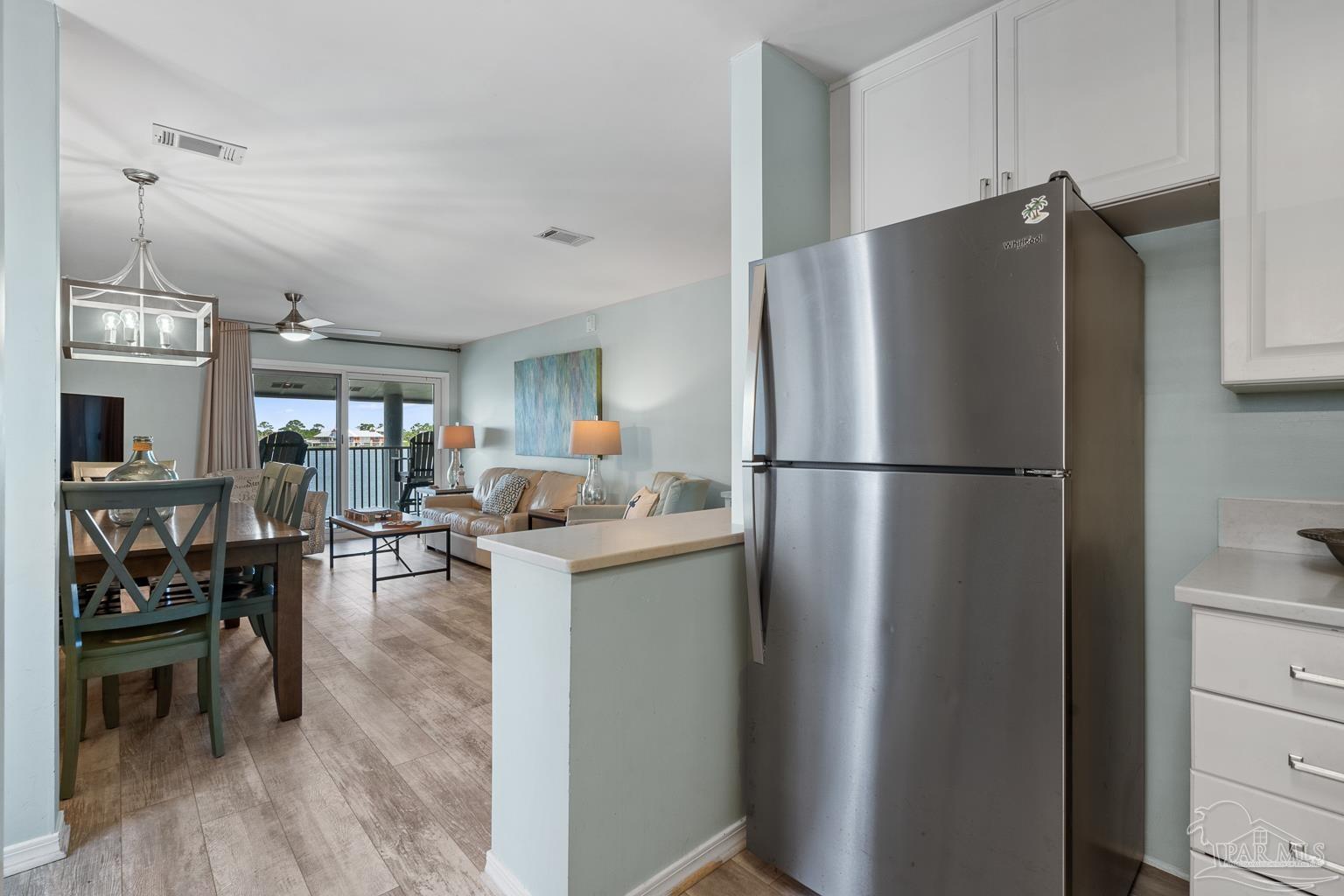 16470 Perdido Key Drive, Unit A 24 Perdido Key, FL 32507 - Photo 15 of 60 a kitchen with a refrigerator a microwave oven dining table and chairs