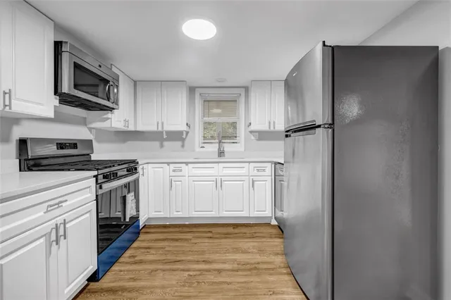 a kitchen with stainless steel appliances granite countertop a refrigerator stove a sink and dishwasher with wooden floor