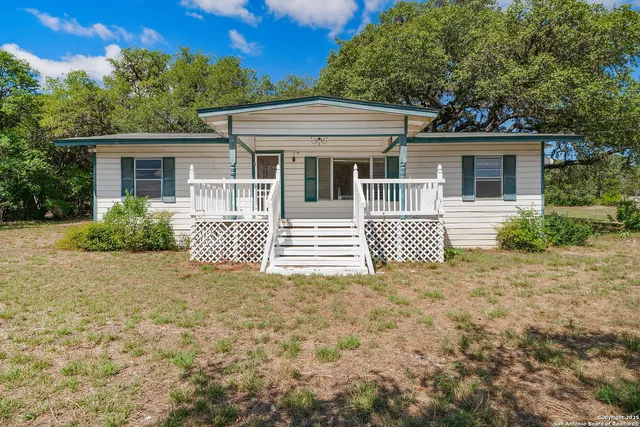 a backyard of a house with large trees and wooden fence
