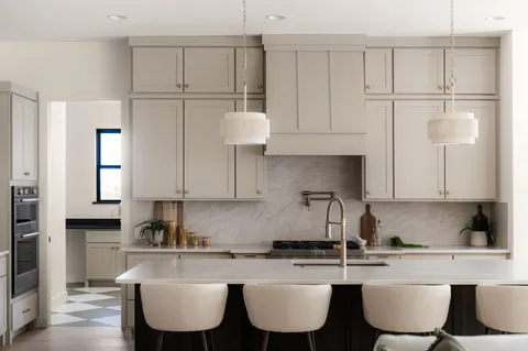a kitchen with stainless steel appliances granite countertop a stove a sink a refrigerator a white table and chairs
