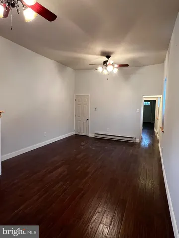 a view of a room with wooden floor and a ceiling fan