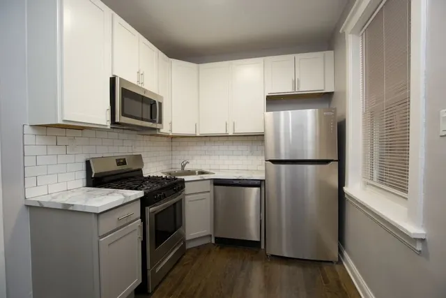 a kitchen with cabinets stainless steel appliances and wooden floor