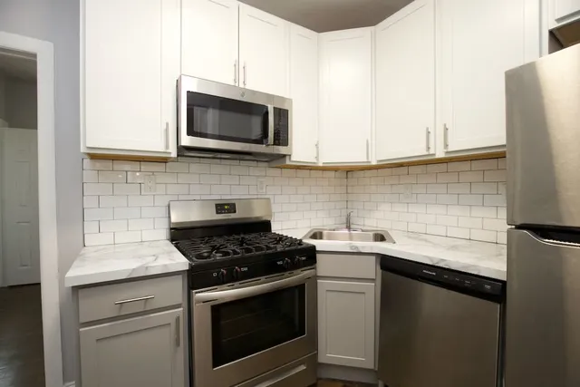 a kitchen with stainless steel appliances granite countertop white cabinets a stove top oven and sink