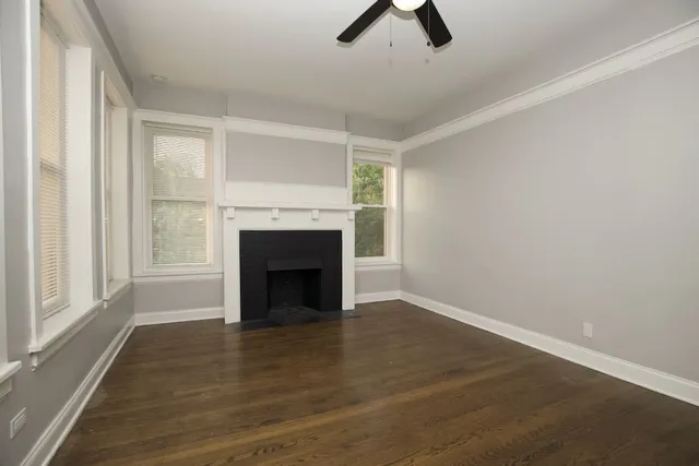 an empty room with ceiling fan window and fireplace