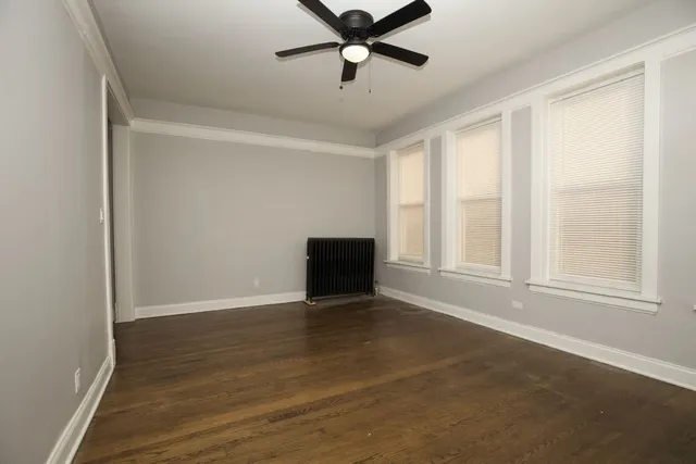 a view of an empty room with window and wooden floor