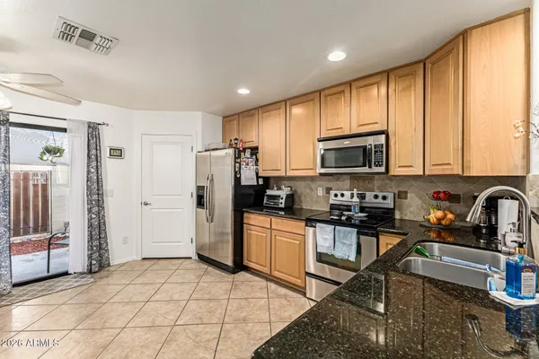 a kitchen with stainless steel appliances granite countertop a stove a sink dishwasher a refrigerator and a microwave with wooden floor