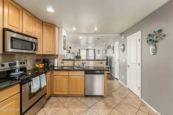 a kitchen with stainless steel appliances granite countertop a stove top oven a sink dishwasher and a refrigerator