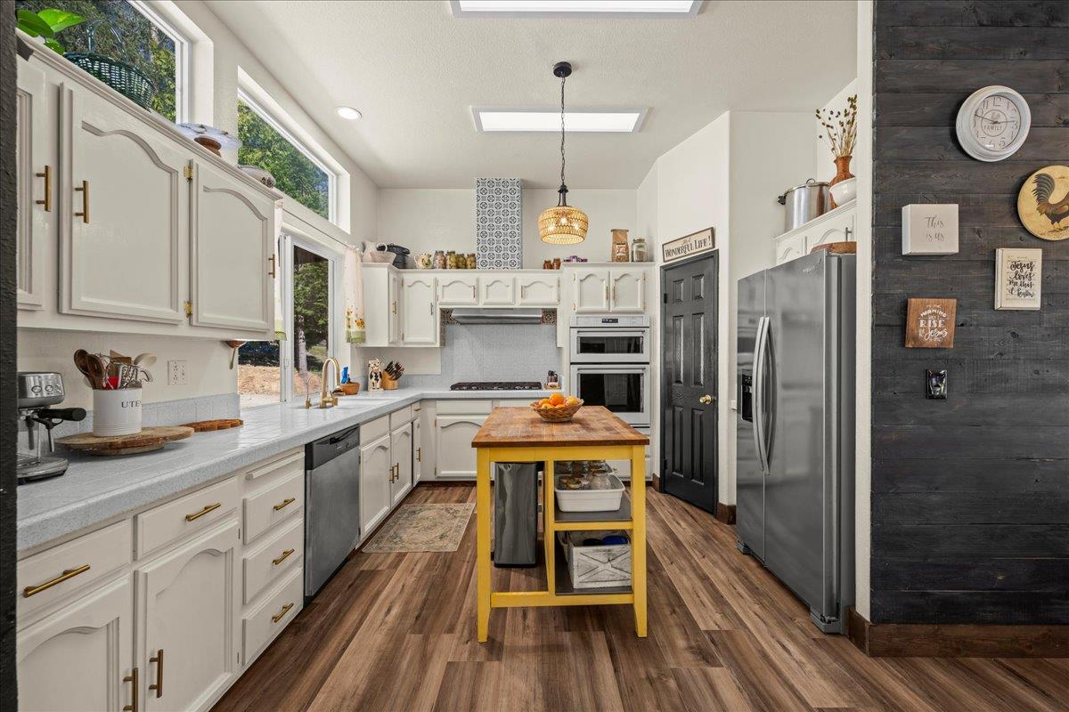 5351 Cosumnes Mine Road Somerset, CA 95684 - Photo 12 of 66 a kitchen with stainless steel appliances granite countertop a refrigerator a sink dishwasher a stove and white cabinets with wooden floor