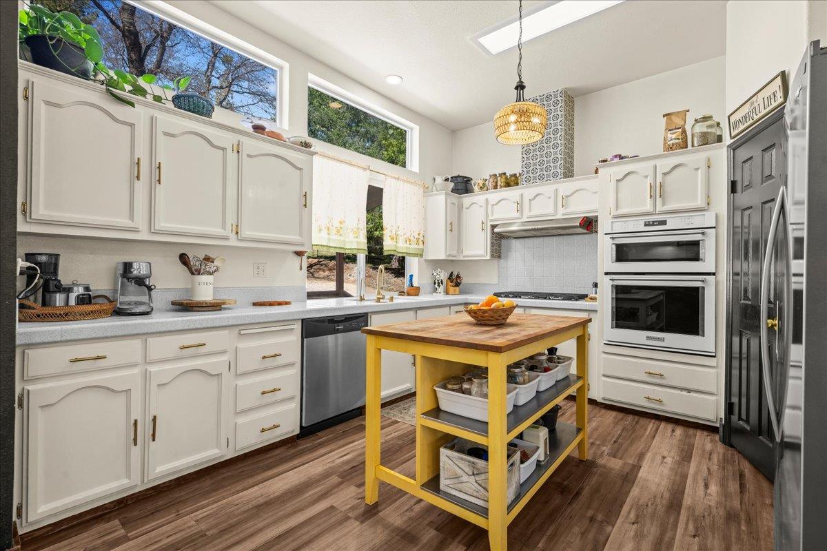 5351 Cosumnes Mine Road Somerset, CA 95684 - Photo 6 of 66 a kitchen with stainless steel appliances granite countertop a stove a sink dishwasher and white cabinets with wooden floor