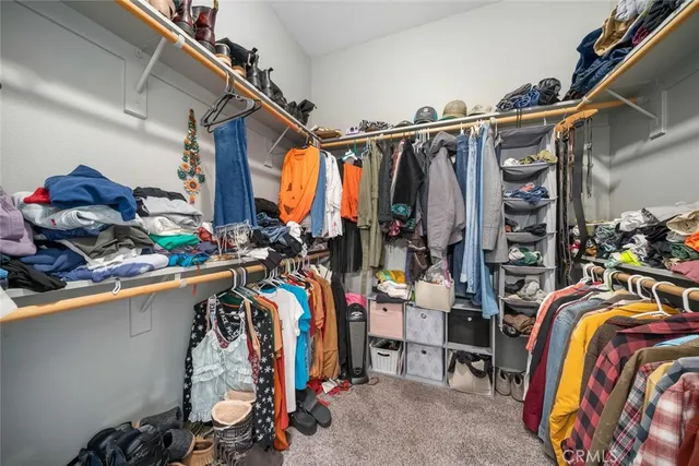 a view of walk in closet with clothes and shoes