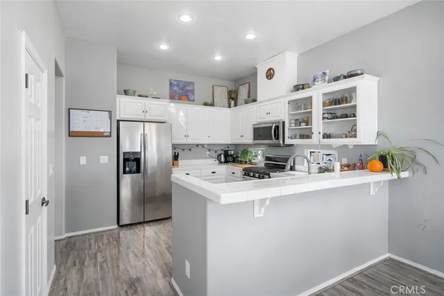 a kitchen with stainless steel appliances a refrigerator a stove a sink dishwasher and white cabinets with wooden floor