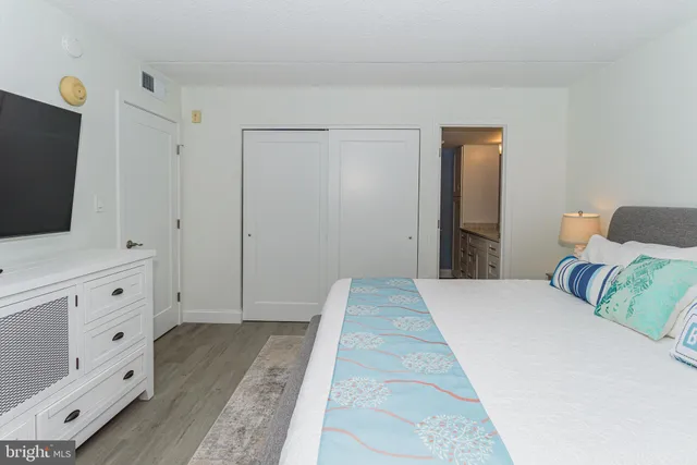 a bedroom with a bed and a flat tv screen on dresser