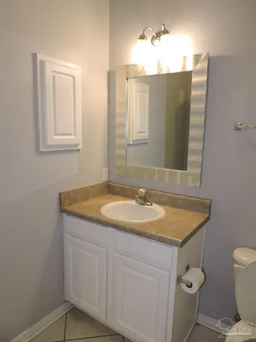 a bathroom with a granite countertop sink toilet and mirror