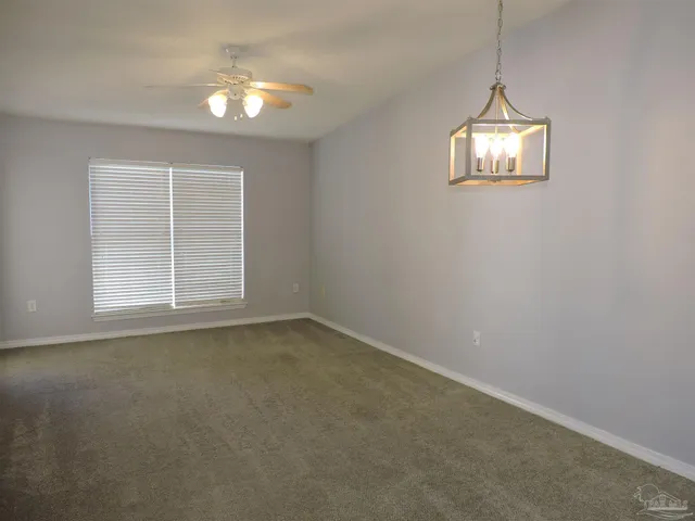 an empty room with windows and chandelier fan
