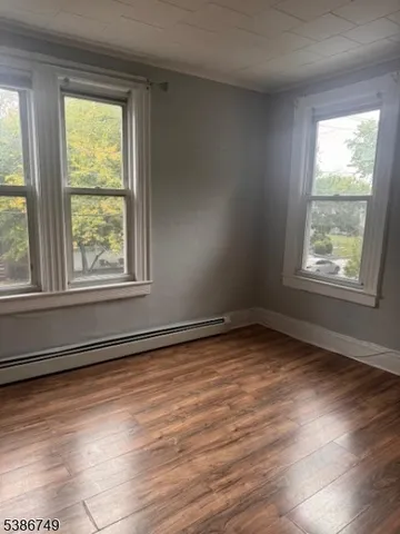 a view of an empty room and wooden floor and a window