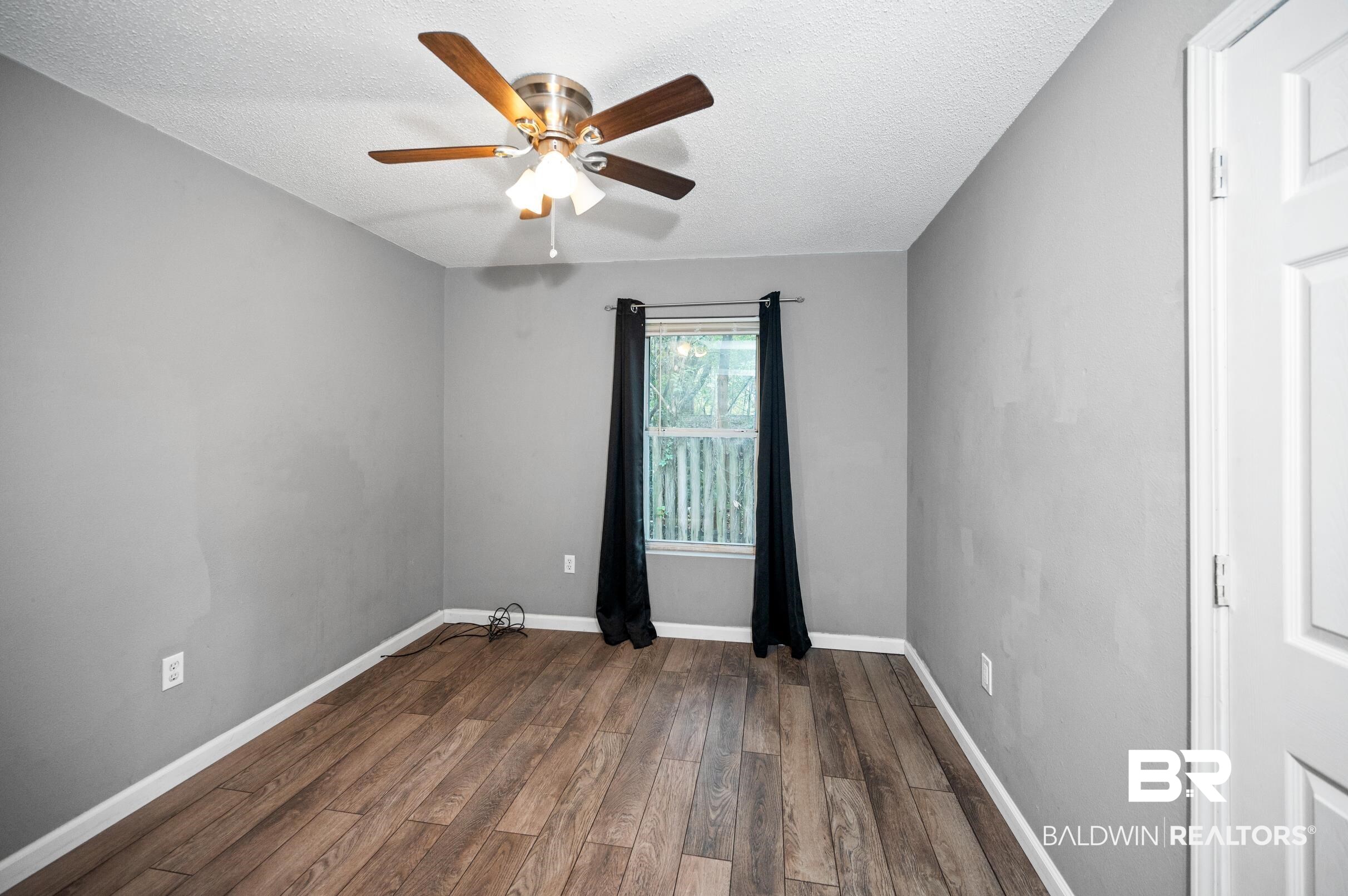 906 North Cedar Street Foley, AL 36535 - Photo 12 of 24 Spare room with ceiling fan, dark hardwood / wood-style floors, and a textured ceiling
