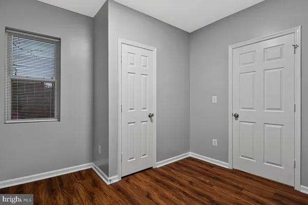 a view of an empty room with closet and wooden floor