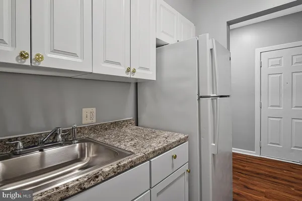 a kitchen with granite countertop a sink and refrigerator