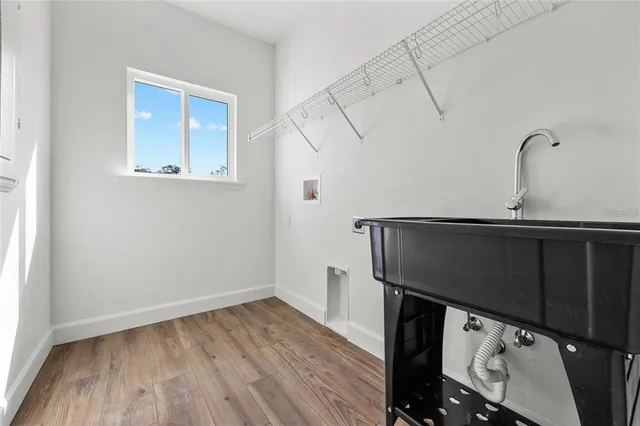 a kitchen with a sink a microwave and wooden floor