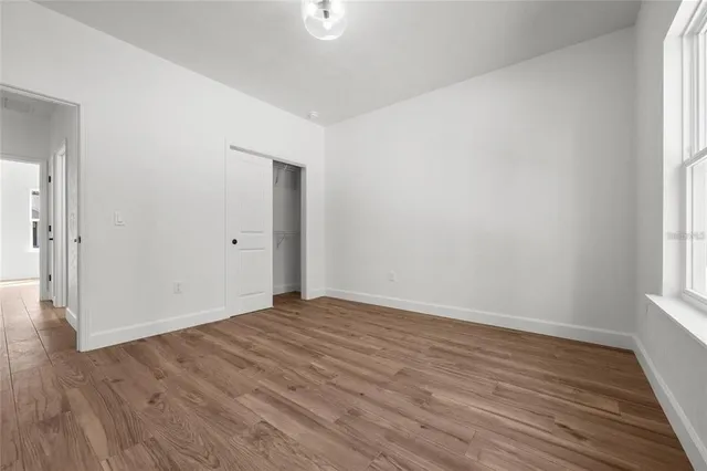 a view of an empty room with wooden floor and a window