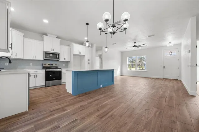 a large kitchen with stainless steel appliances granite countertop a stove oven and a wooden floors