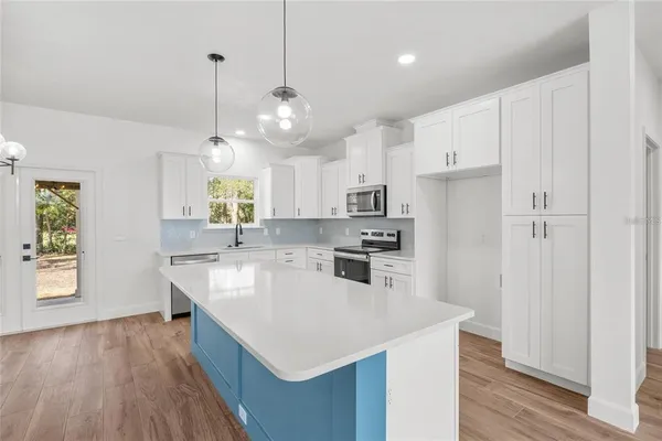 a large kitchen with stainless steel appliances a large center island attached withe living room