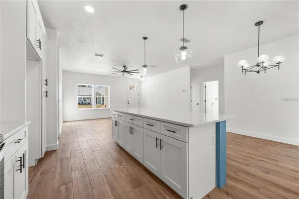 a large kitchen with cabinets wooden floor and a chandelier