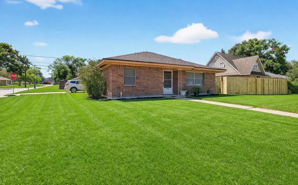 a view of a house with a yard and a large tree