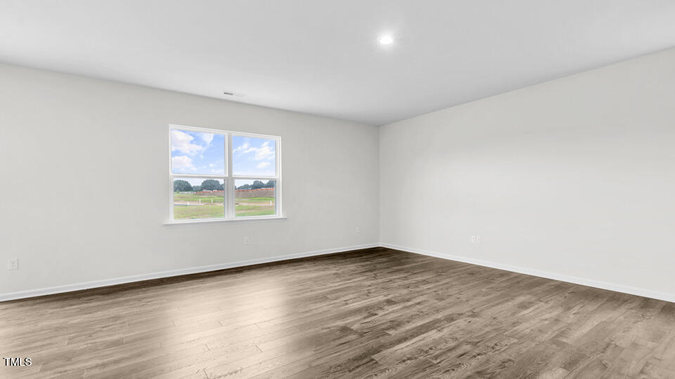 812 Comice Pear Way Willow Spring, NC 27592 - Photo 12 of 42 an empty room with wooden floor and windows