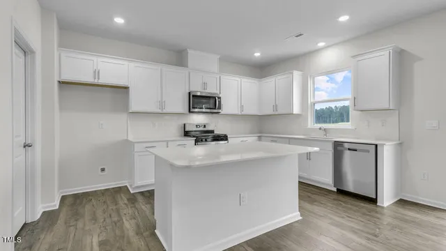 a kitchen with kitchen island white cabinets appliances and a window